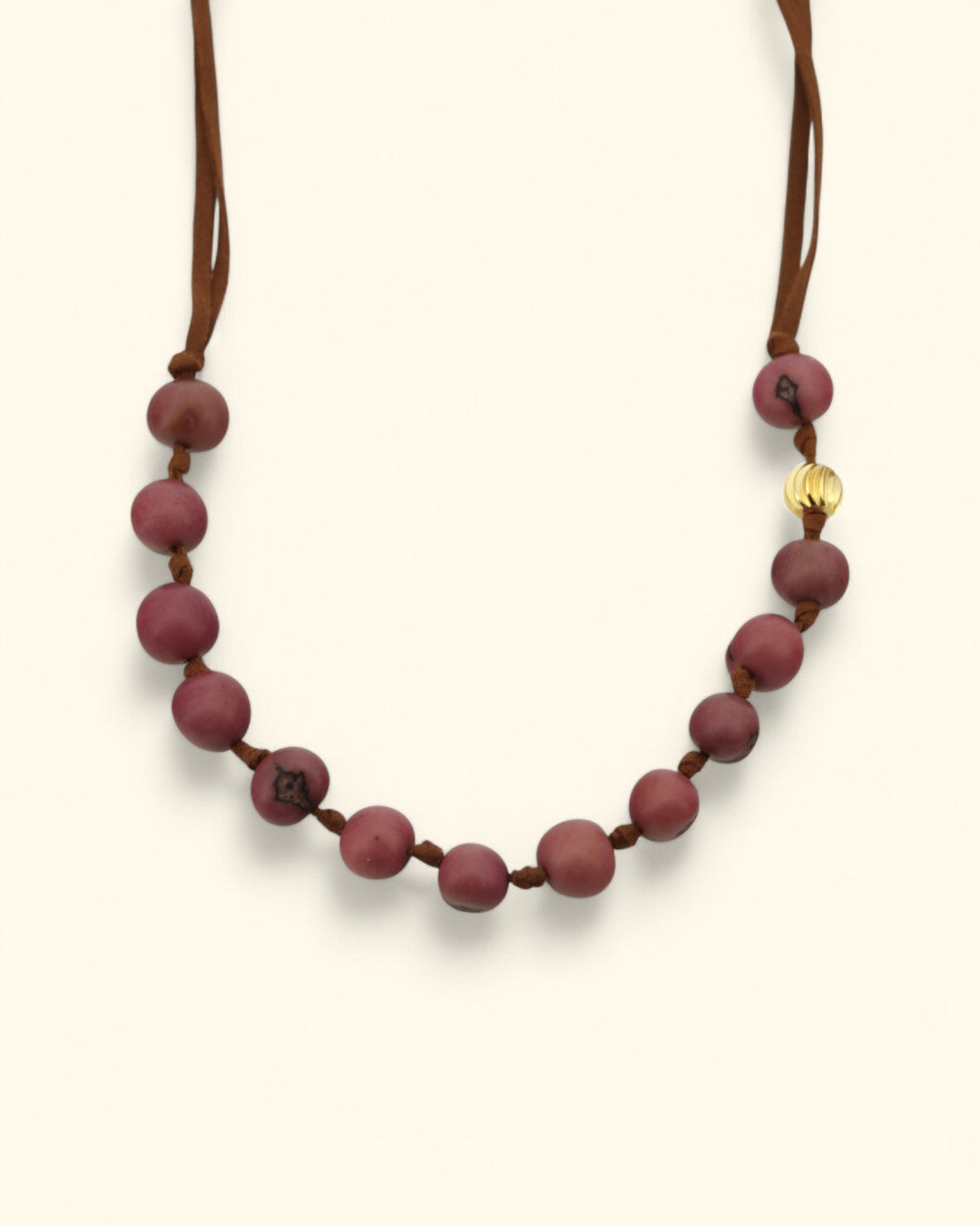 Necklace with maroon beads and a gold charm on a white background