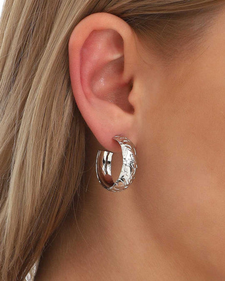 Silver hammered hoop earring worn on ear