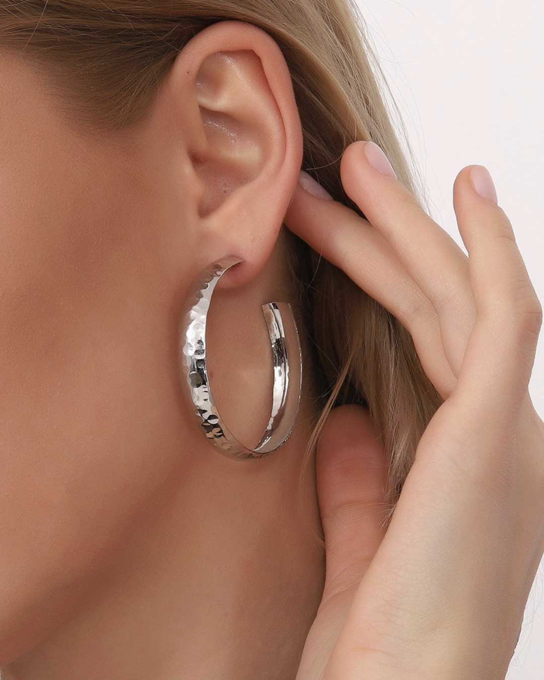 Large hammered silver hoop earrings on model