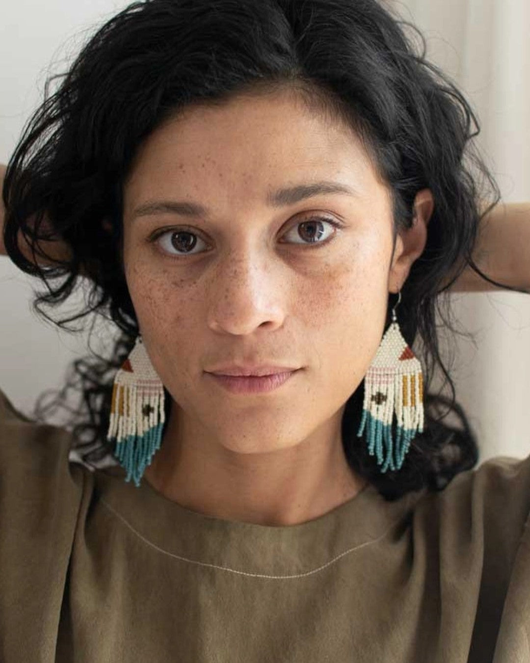 Woman wearing large earrings with a neutral background
