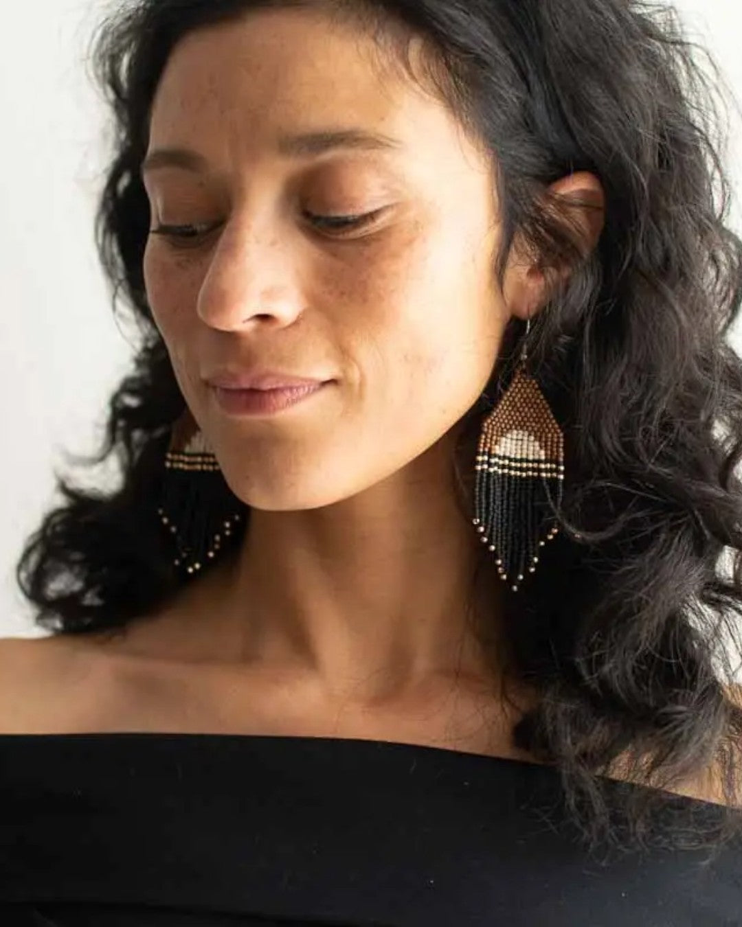 Woman wearing beaded earrings with a neutral background