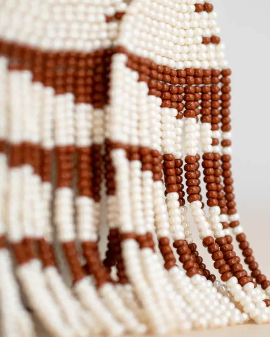 Close-up of a beaded pattern with brown and white beads on a blurred background