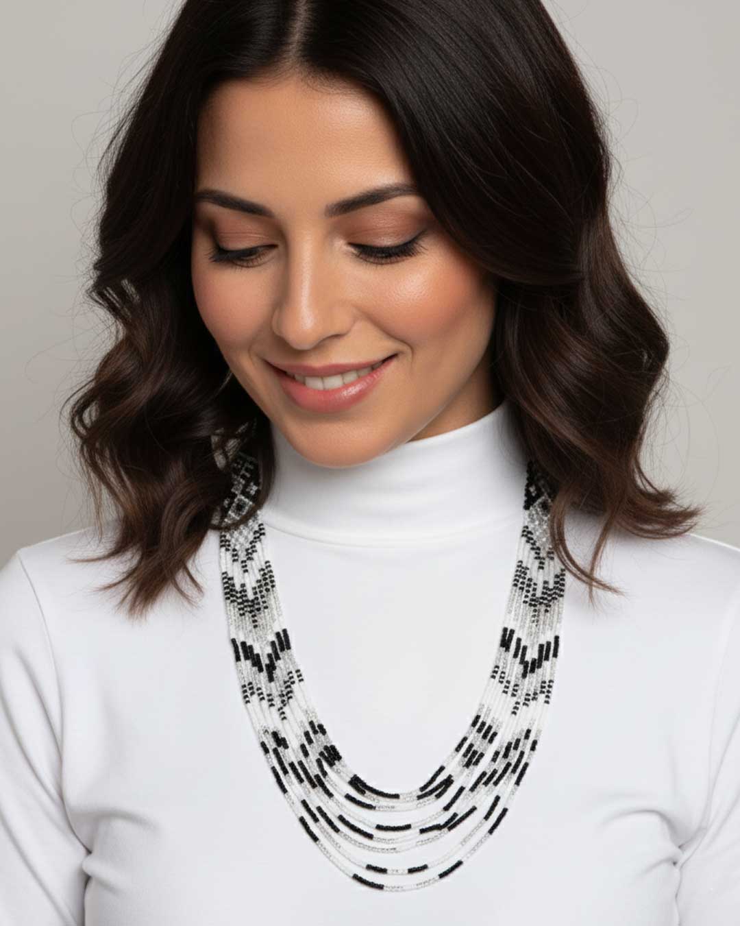 Woman wearing a black and white patterned necklace with a plain background