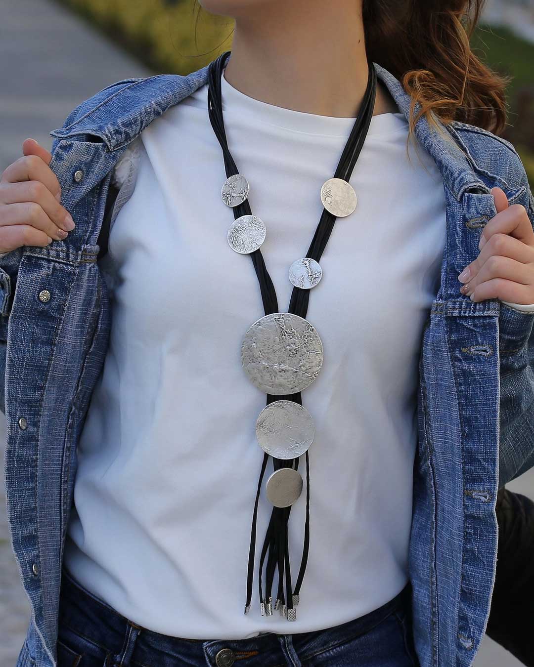 Person wearing a white shirt with a decorative bolo tie and a denim jacket.