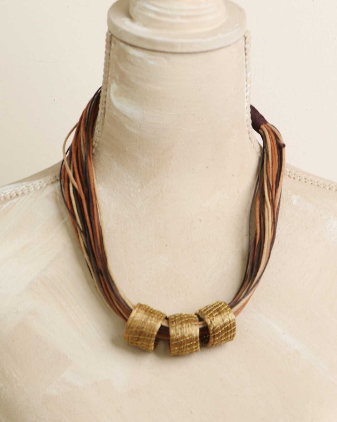 Brazilian golden grass necklace with woven rings on mannequin