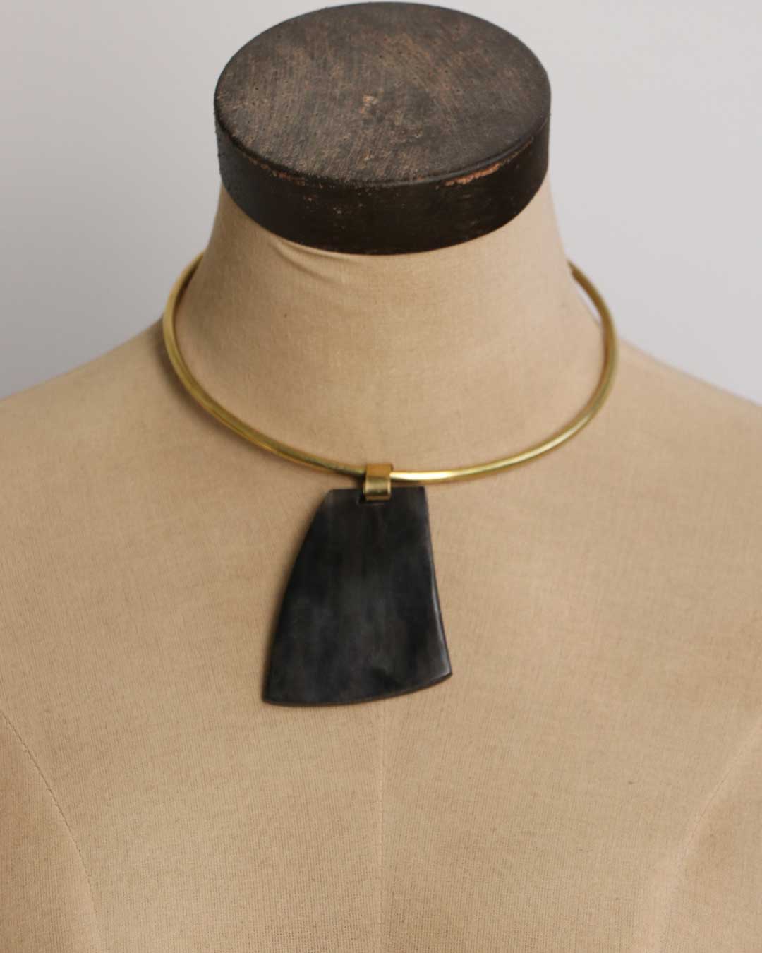 Ankole horn pendant brass choker necklace displayed on a fabric dress form, showing pendant drape and collar fit from the front