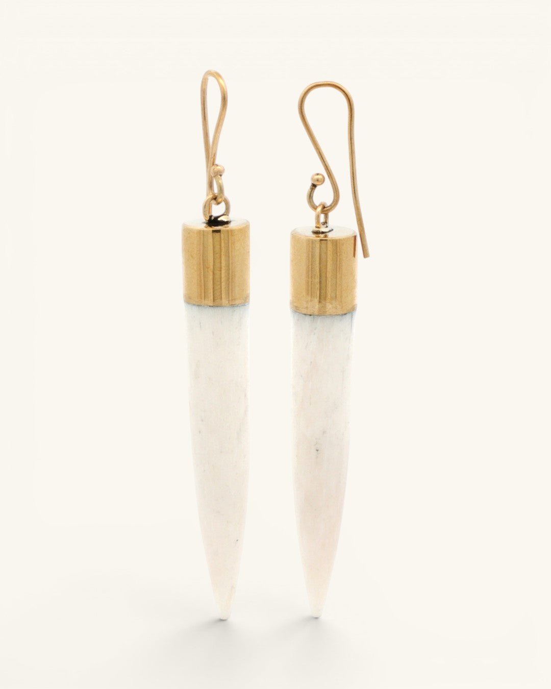 Bone spike dangle earrings with ridged brass caps standing upright, side view highlighting hook hardware and carved texture