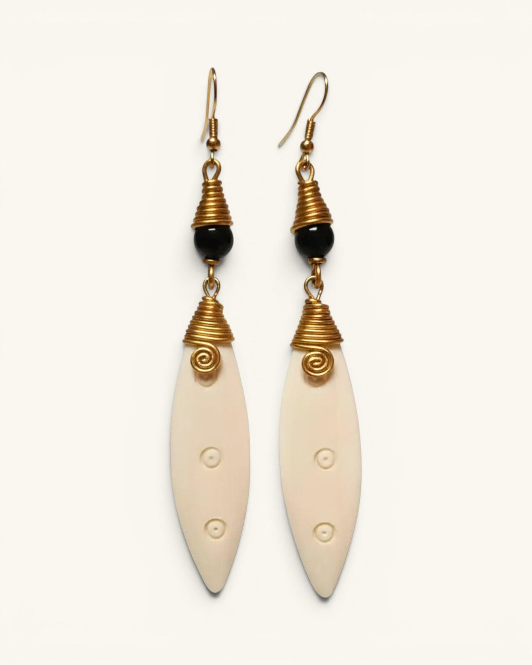Hand-coiled brass and carved bone drop earrings with black bead, front view on white background showing both pieces