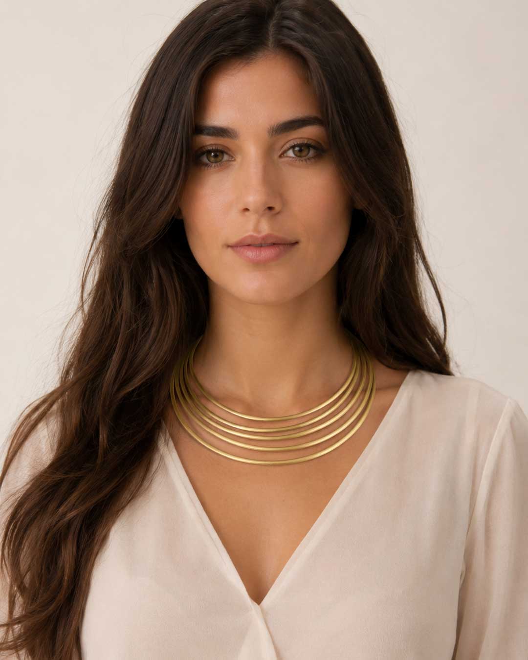Brass five-band collar necklace worn by model in white v-neck top, front view showing fit and drape at the neckline