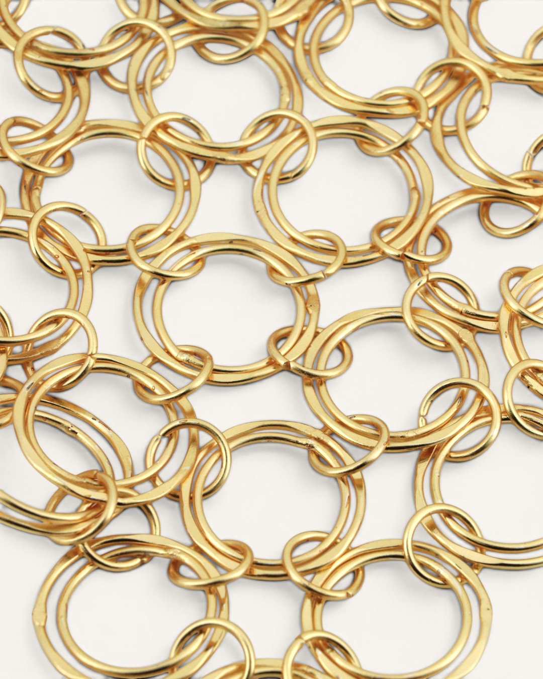 Close-up detail of hand-hammered brass ring bib necklace showing interlocked open brass rings and hammered texture