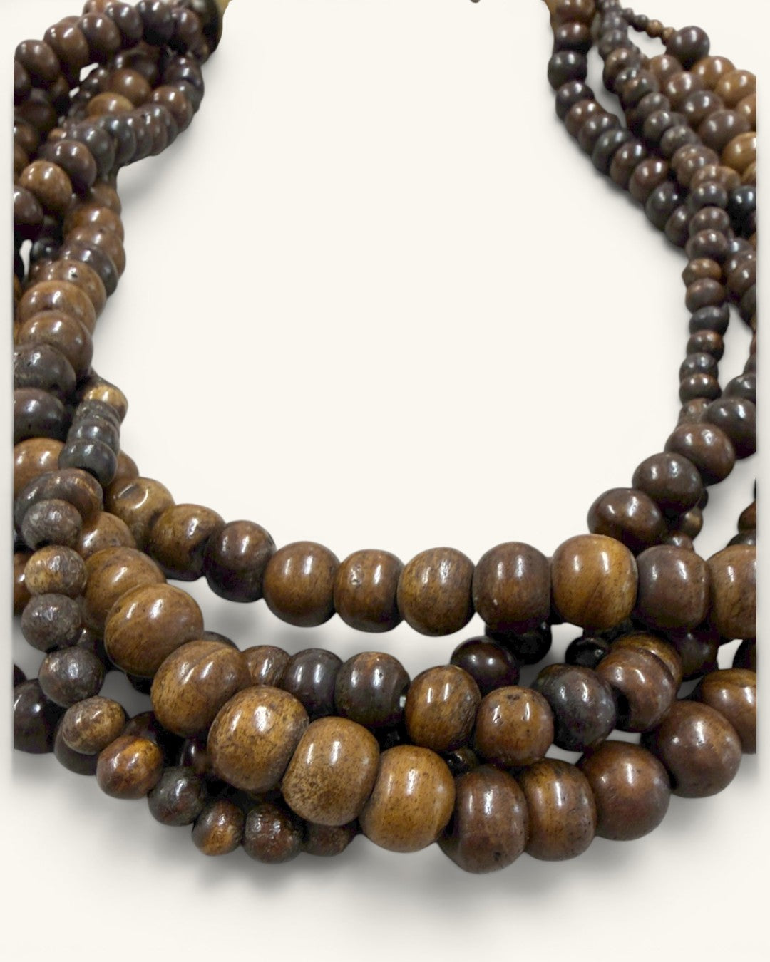 Close-up detail of varied-size brown wooden beads across five strands, showing surface texture and mixed sizing