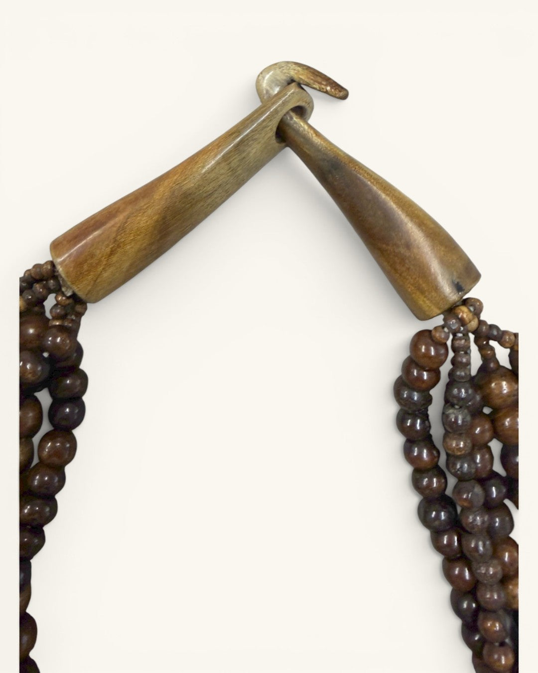 Close-up detail of the wooden bar-and-hook toggle clasp on the brown five-strand beaded necklace, unclasped