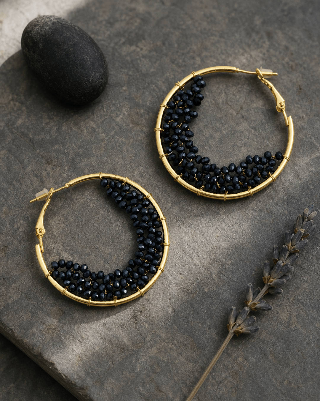 Black beaded crescent hoop earrings on a soft misty background