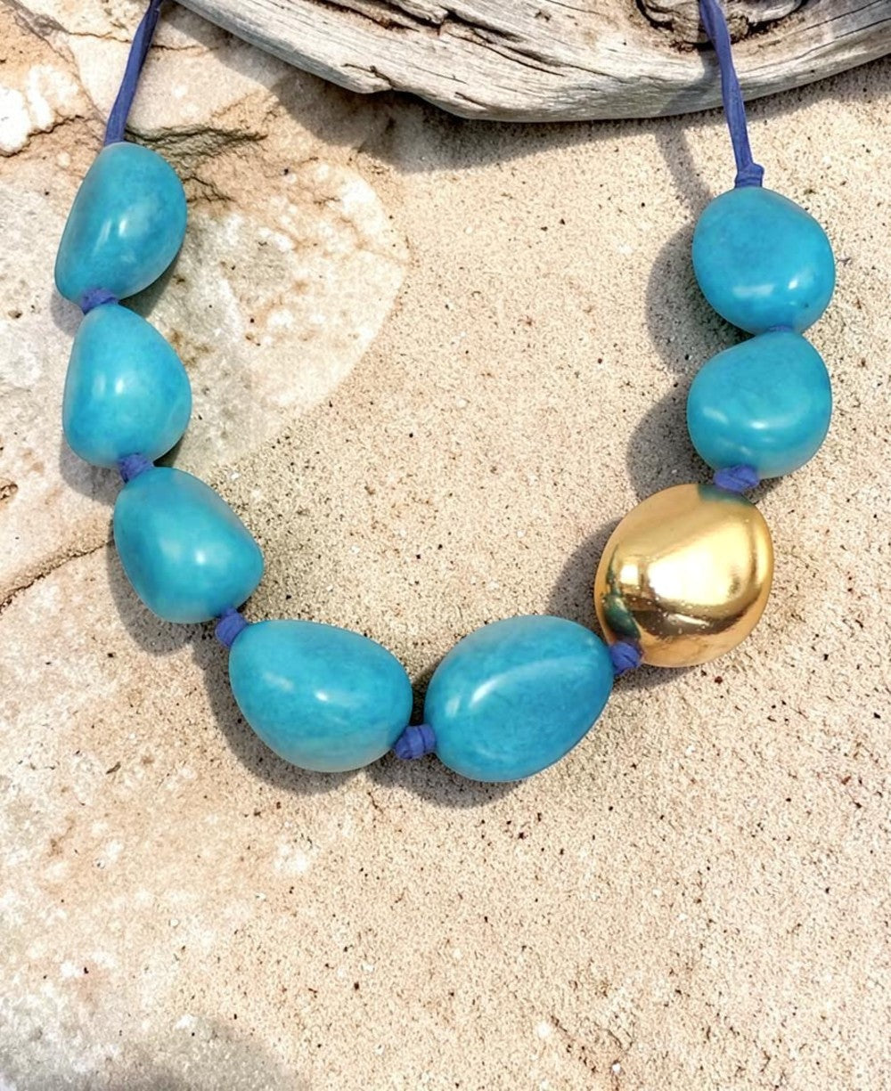 Cultural Elements statement necklace with turquoise tagua pods and a single 24K gold plated tagua pod on a blue cord.