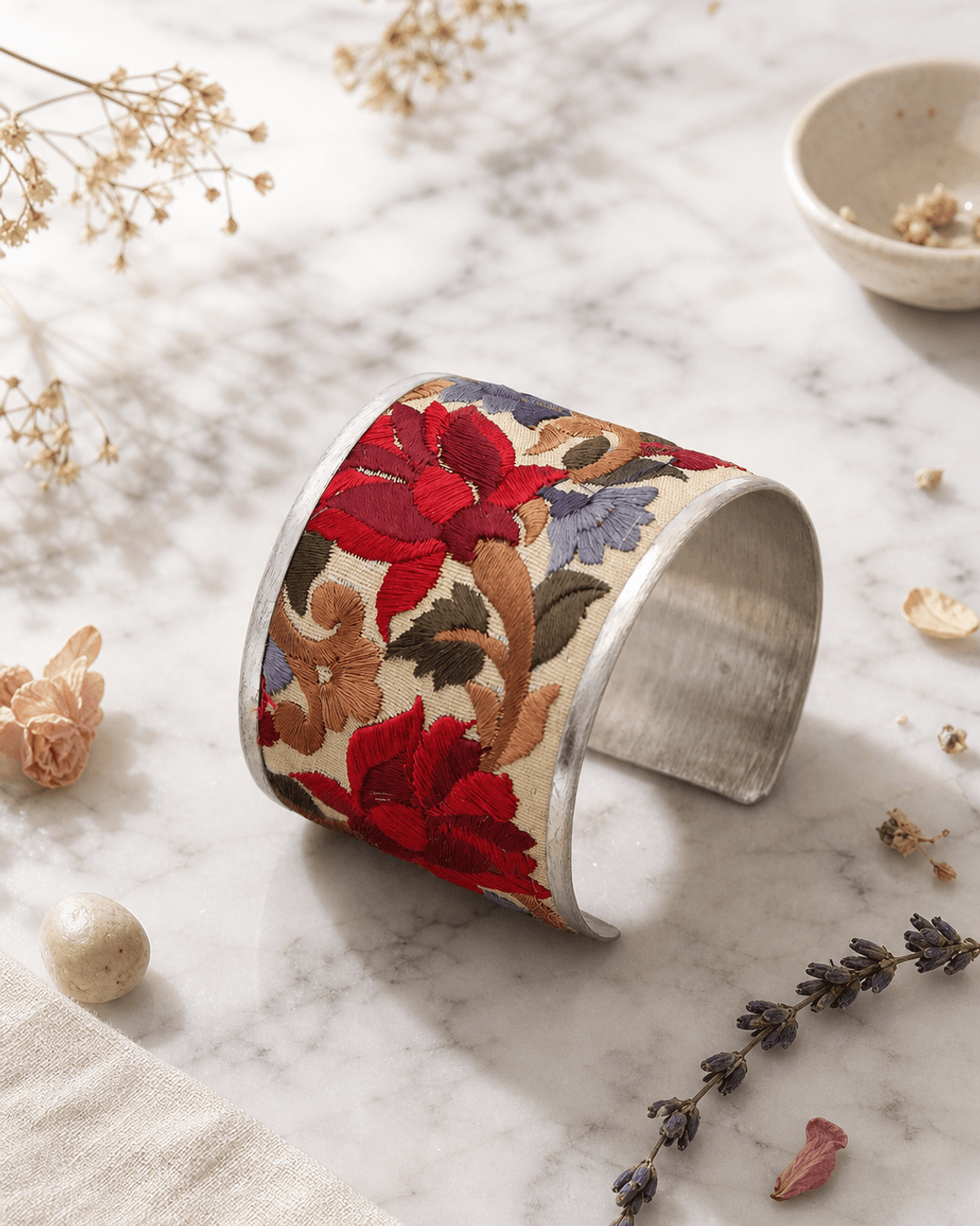 Embroidered lotus flower cuff bracelet displayed on white marble surface