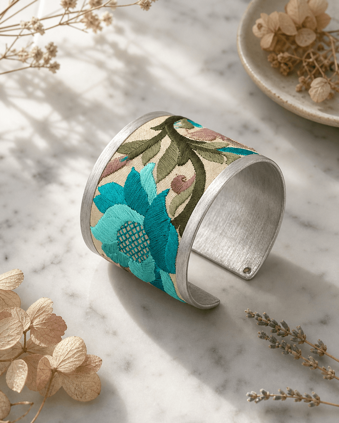 Turquoise embroidered lotus cuff bracelet displayed on white marble surface