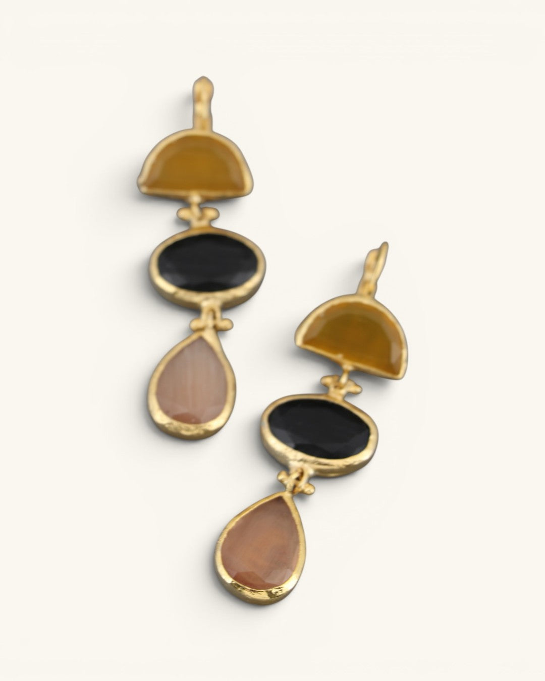 Close-up detail of gold-plated triple stone cat eye drop earrings showing gold bezel connectors and faceted stones