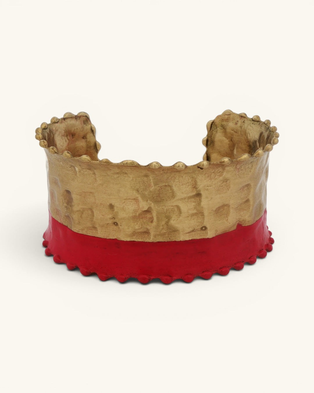 Hand-hammered brass cuff bracelet with red painted lower band and scalloped edges, straight-on front view on white background