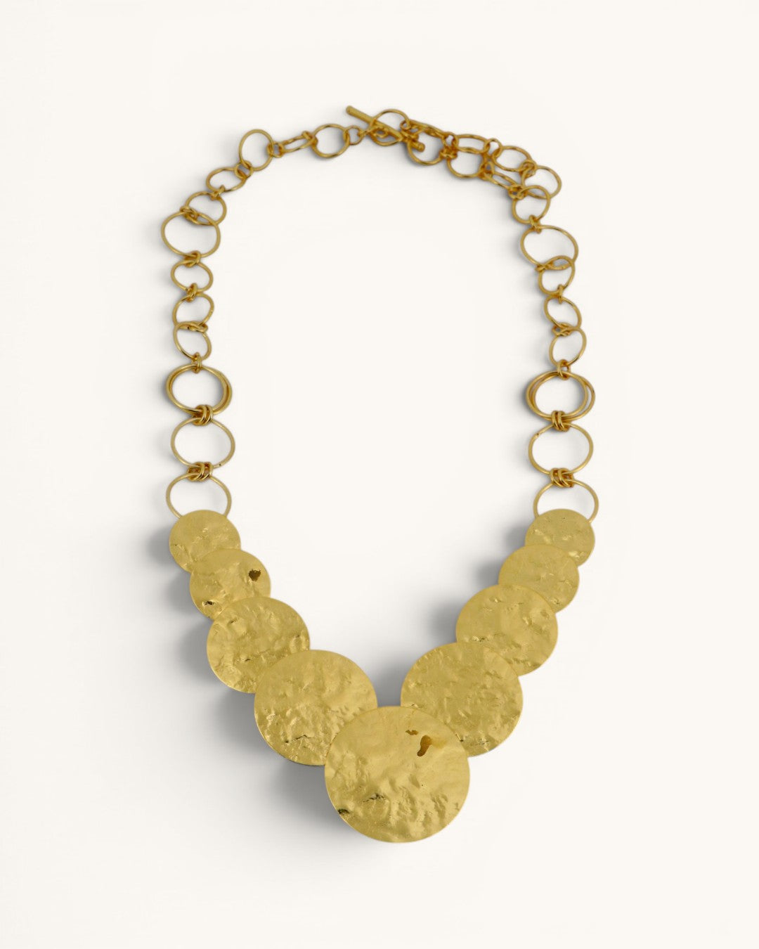 Hammered brass cascading disc necklace full front view on white background, toggle clasp and open link chain visible