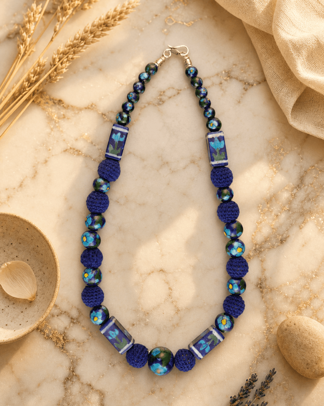 Hand-Painted Floral Ceramic Bead Necklace with Crochet Accents — necklaces, editorial marble warm lifestyle photo