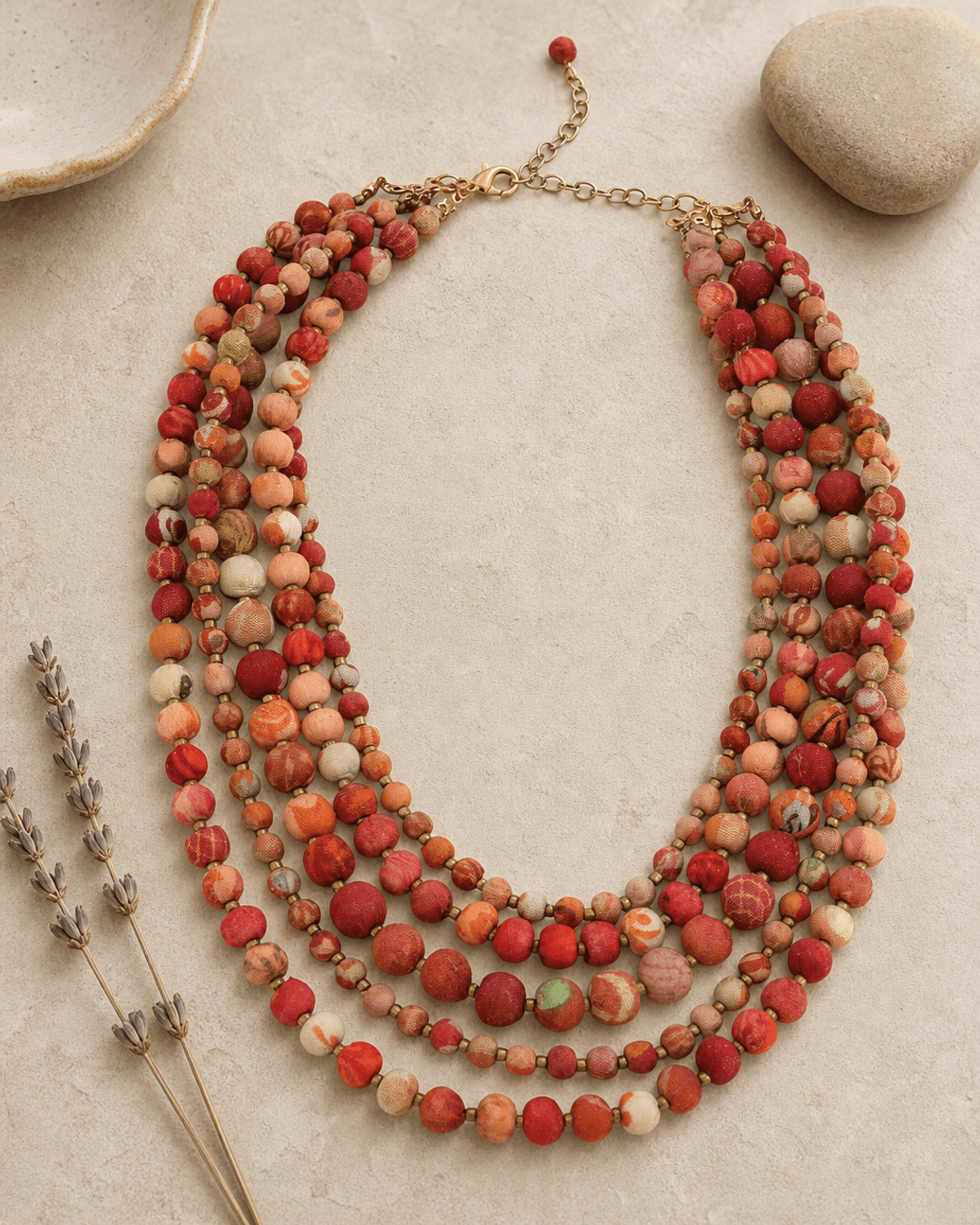 Handmade kantha five-strand layered necklace displayed on a vanity, featuring colorful fabric-wrapped beads and boho textile design