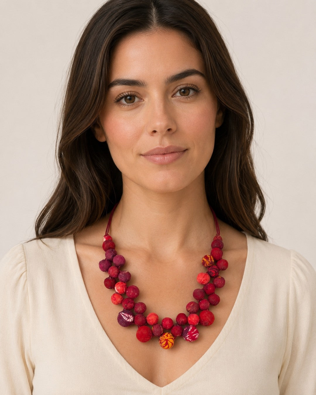 Kantha recycled textile layered bead necklace in red worn by a woman in a white v-neck top, showing length at collarbone