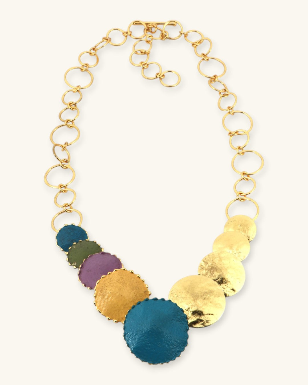 Side-angle flat lay of patina brass disc cascade necklace displaying chain length and profile of individual disc pendants