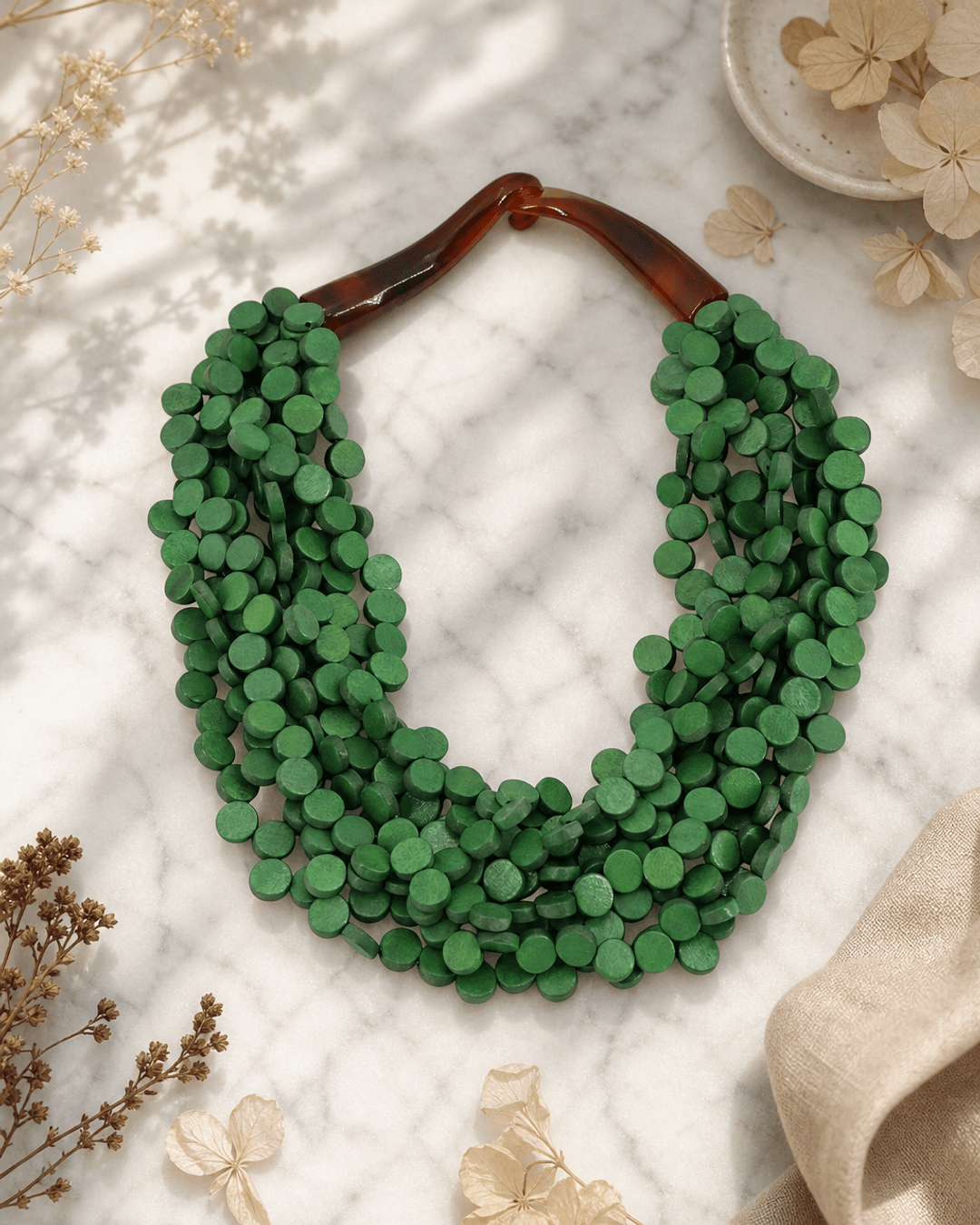 Twisted green wood disc pendant necklace on white marble surface