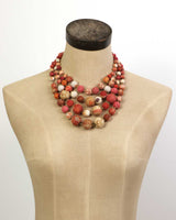 Multistrand beaded necklace on a mannequin bust with a plain background