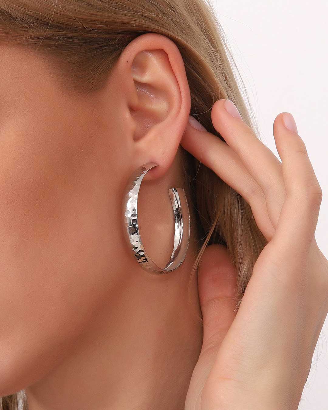 Large hammered silver hoop earring worn on ear