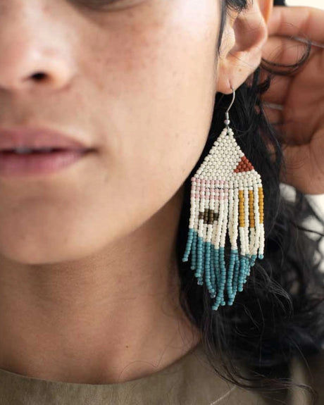 Close-up of a person wearing a beaded earring with a colorful design.