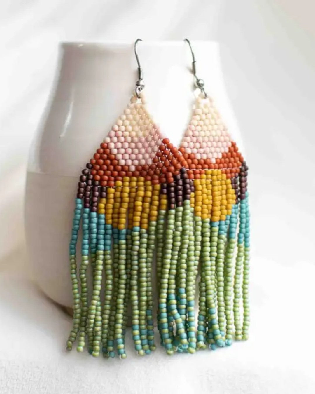 Colorful beaded earrings on a white stand with a white background