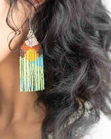Colorful beaded earring worn by a person with wavy hair.