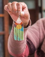 Hand holding a colorful beaded earring with a blurred background