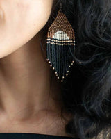 Close-up of a person wearing a beaded earring with geometric design.