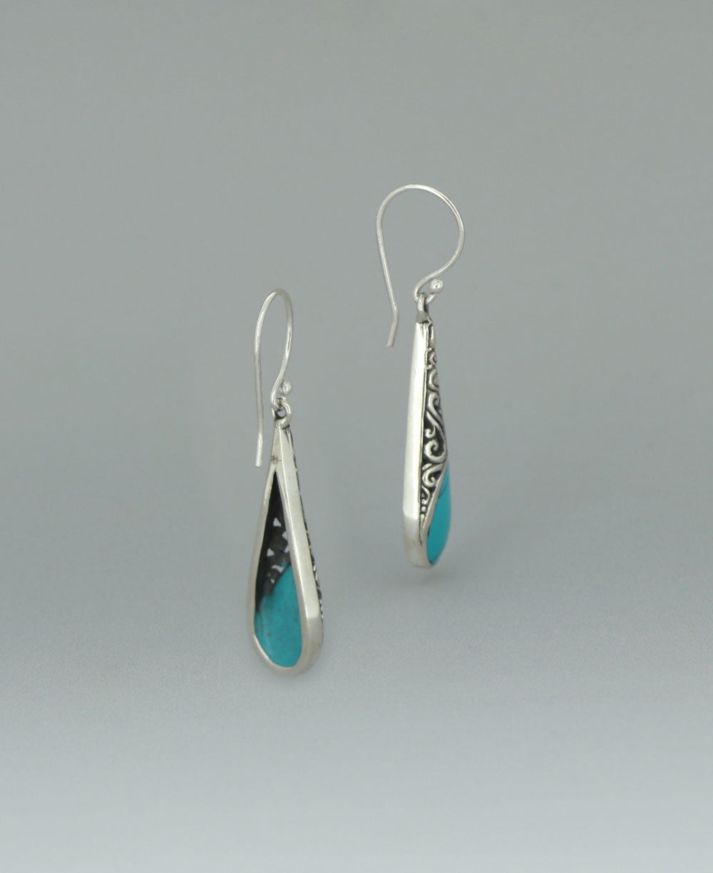 Sterling silver Reconstituted Turquoise earrings, emphasizing the elongated teardrop shape and the striking contrast between the turquoise and filigree design