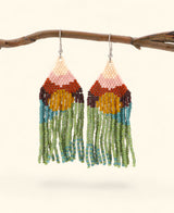 Colorful beaded earrings hanging from a branch on a light background