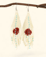 Pair of beaded earrings with red and blue beads hanging from a branch.