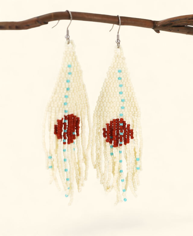Pair of beaded earrings with red and blue beads hanging from a branch.