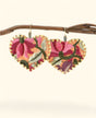 Heart-shaped embroidered earrings on a branch against a white background
