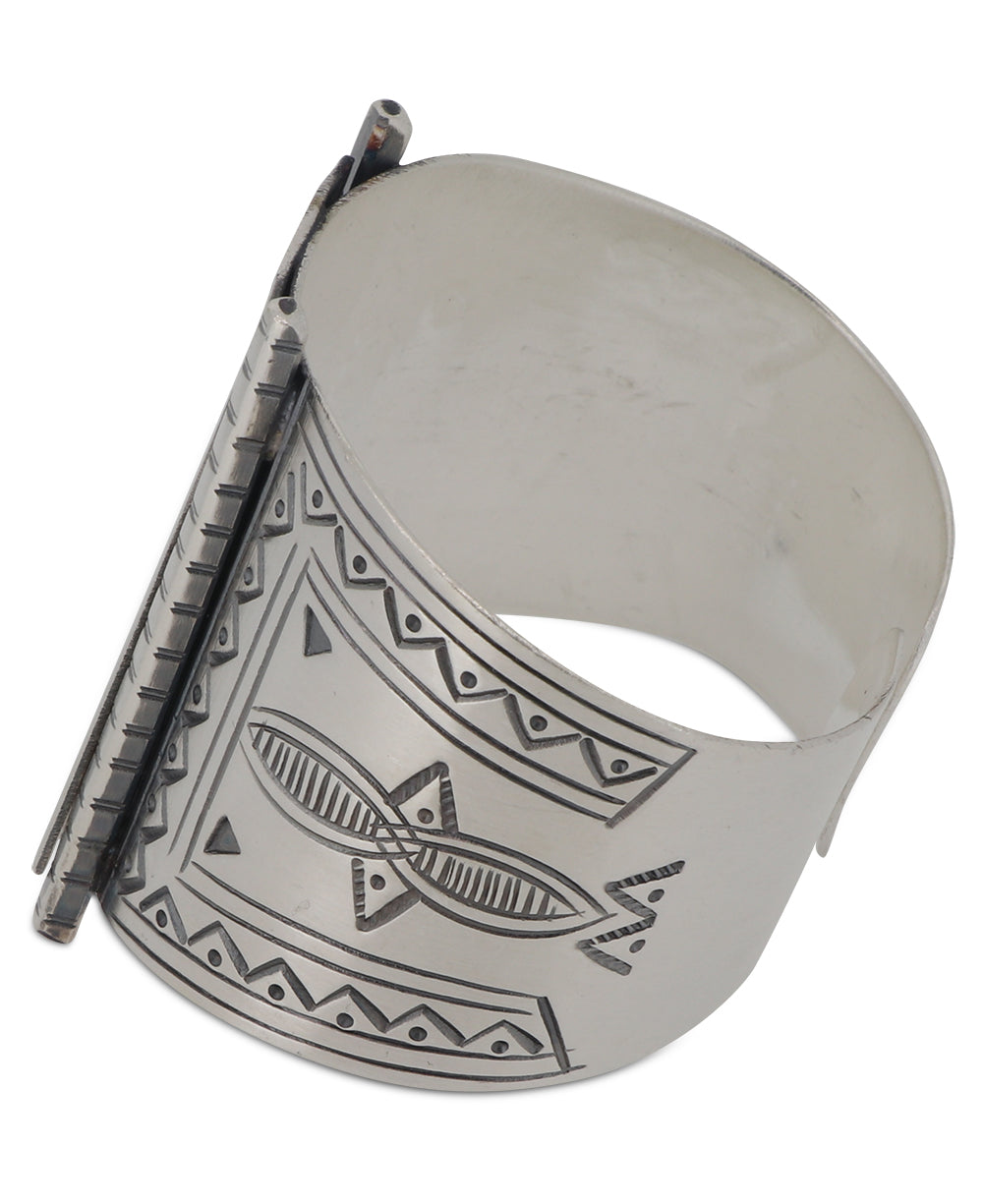 Close-up view of detailed tribal designs on silver wide cuff.