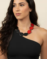 Woman wearing a black and red necklace against a beige background