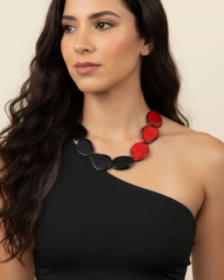 Woman wearing a black and red necklace against a beige background
