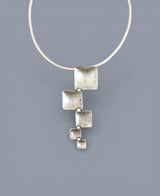 Silver necklace with a geometric pendant on a gray background