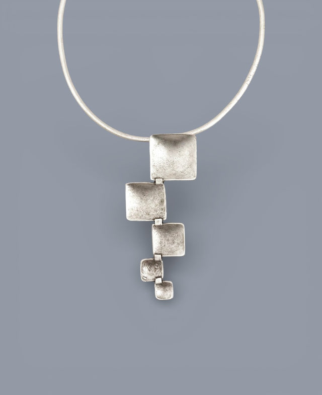 Silver necklace with a geometric pendant on a gray background