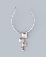 Silver necklace with square pendants on a light gray background