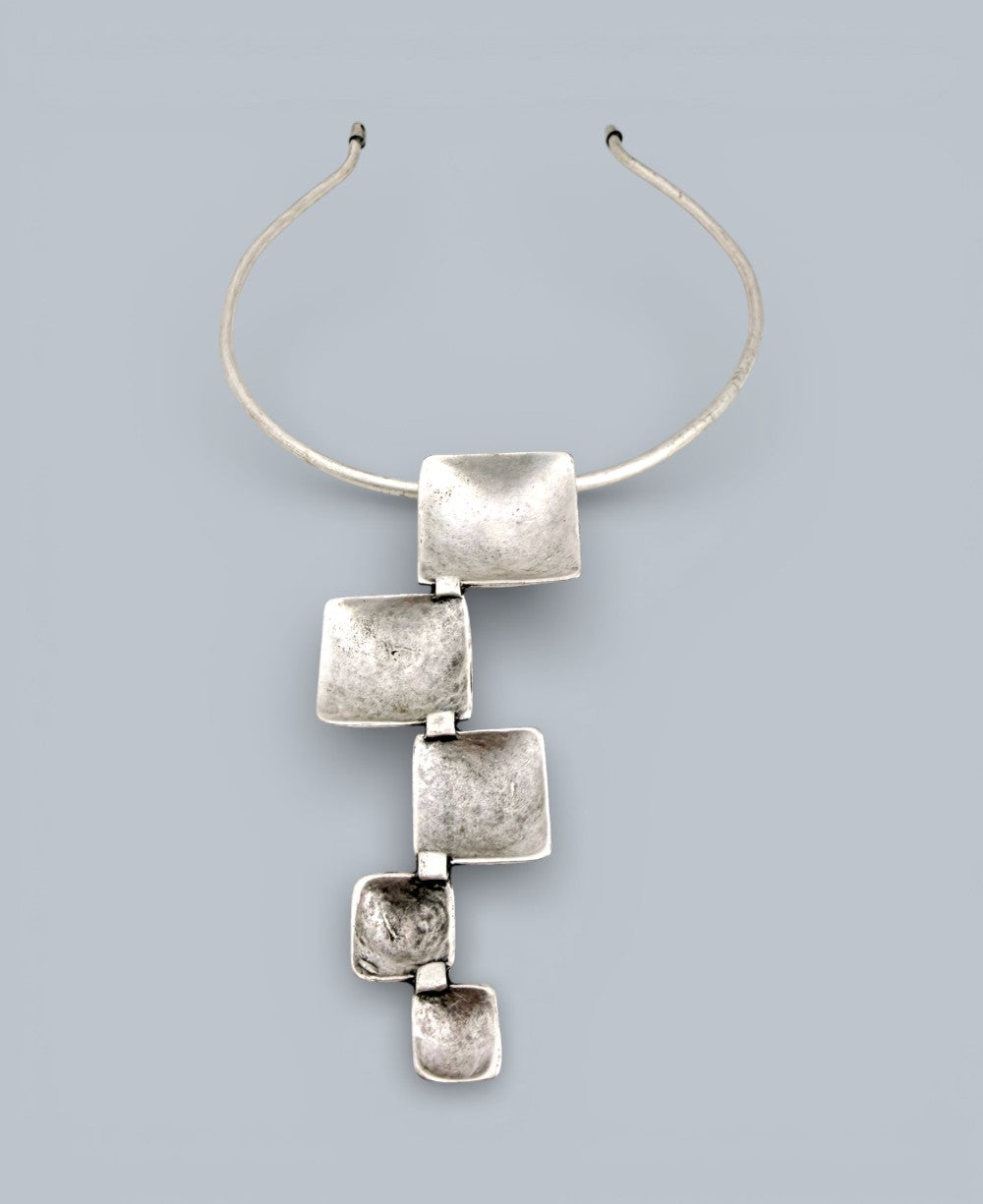Silver necklace with square pendants on a light gray background