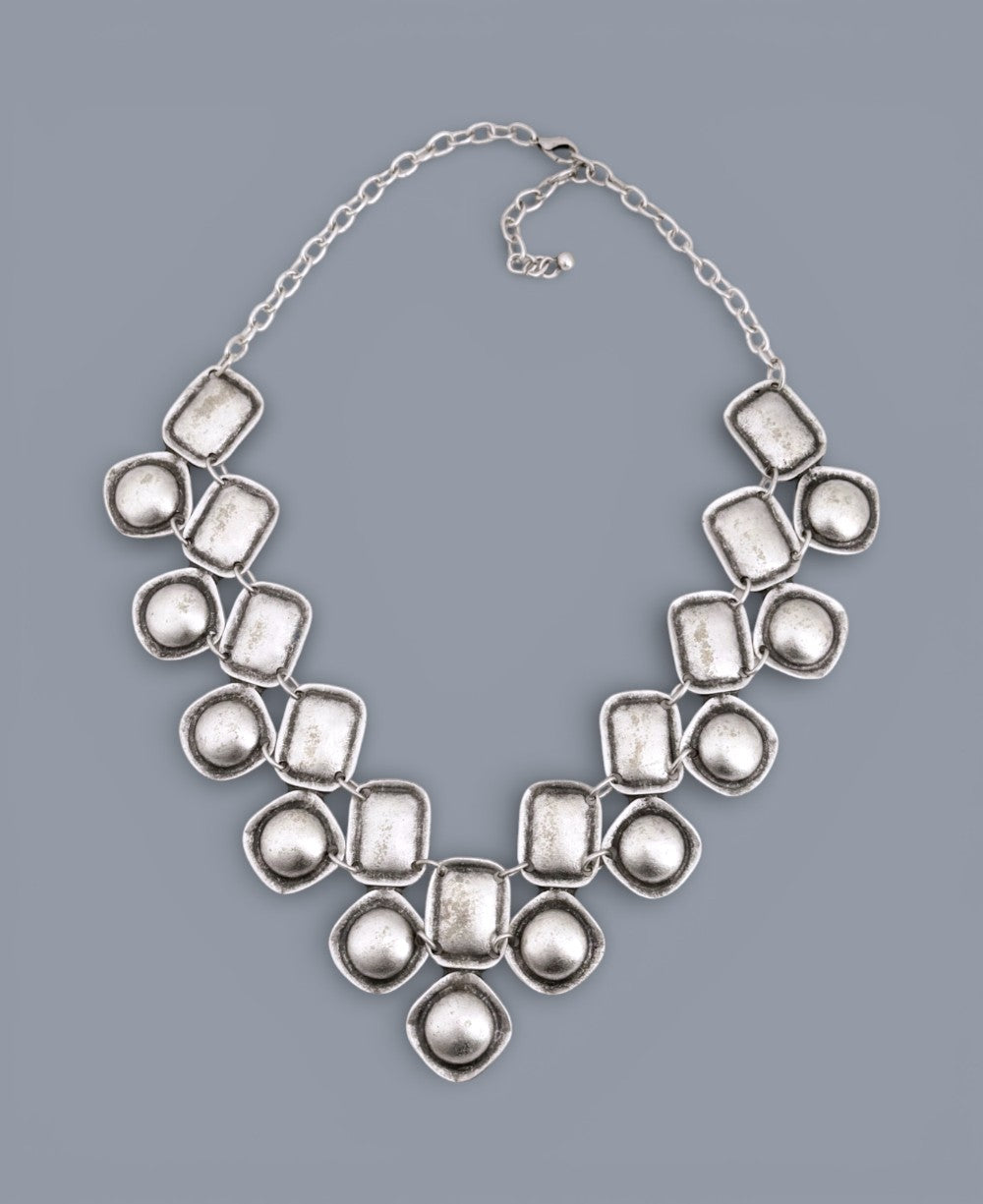 Silver necklace with large, irregularly shaped beads on a gray background