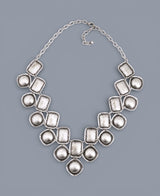 Silver necklace with large, irregularly shaped beads on a gray background