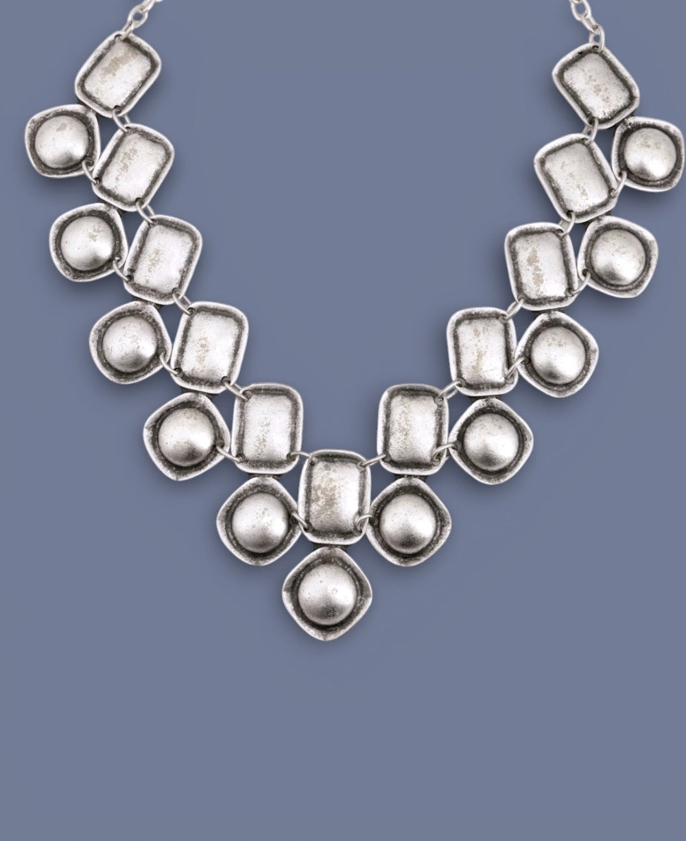 Silver necklace with geometric design on a blue background